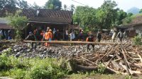 Sejumlah relawan membersihkan material kayu dampak banjir bandang di Desa Gunungsari, Maesan, Bondowoso, Jawa Timur, Jumat (10/1/2025).