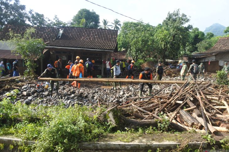 Sejumlah relawan membersihkan material kayu dampak banjir bandang di Desa Gunungsari, Maesan, Bondowoso, Jawa Timur, Jumat (10/1/2025).